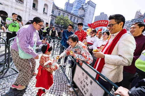 圖為巡游隊(duì)伍沿途給游客送出祝福吉祥的金元寶。澳門特區(qū)政府新聞局供圖