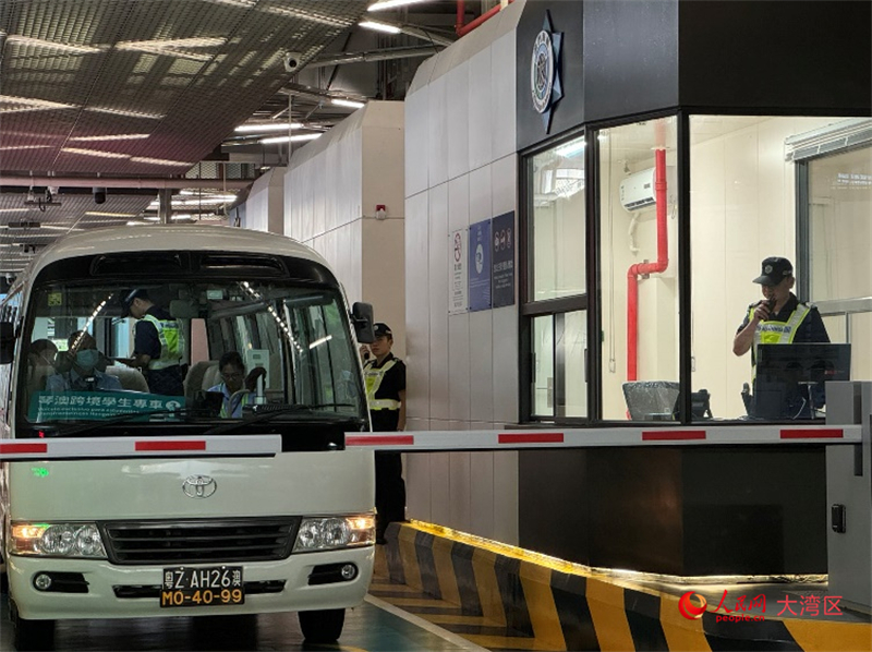 圖為第一輛跨境學(xué)生專車接受澳門海關(guān)登車查驗(yàn)、學(xué)生免下車通關(guān)服務(wù)新舉措。人民網(wǎng)記者 富子梅攝