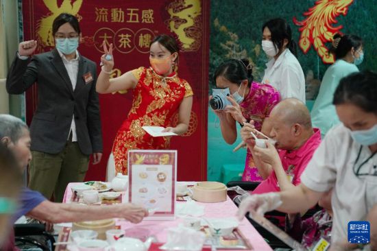 5月24日，在香港松悅園耆和護(hù)養(yǎng)院，香港樂齡社企“軟餐俠”的職員們扮演成“茶樓”經(jīng)理、廚師和接待員，為老人家提供沉浸式茶樓就餐體驗(yàn)。新華社發(fā)（王申 攝）