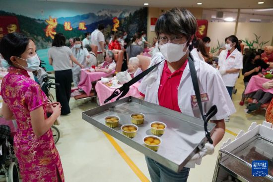 5月24日，在香港松悅園耆和護(hù)養(yǎng)院，身穿白衫的伙計(jì)在“茶樓”售賣茶點(diǎn)，端茶倒水。新華社發(fā)（王申 攝）