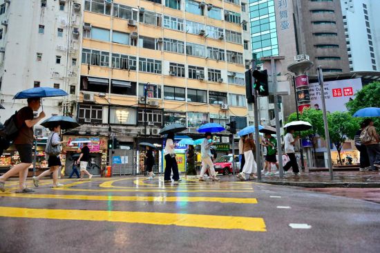 8月2日，人們撐傘走在雨中。當(dāng)日，香港天文臺(tái)再一次發(fā)出黑色暴雨警告信號(hào)。這是一周內(nèi)連續(xù)發(fā)出的第二個(gè)黑色暴雨警告。新華社記者 朱煒 攝